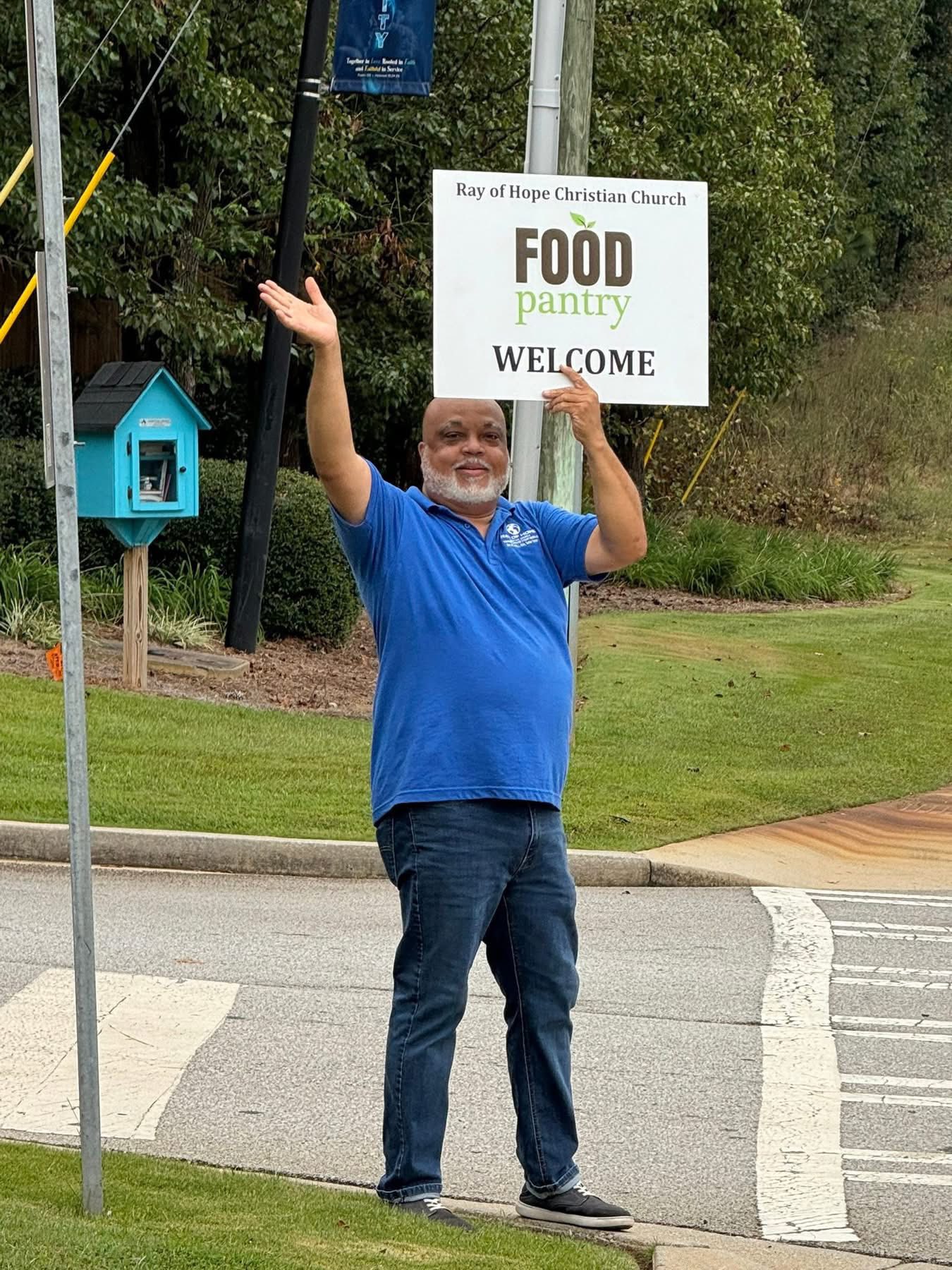 Community member holding a food pantry welcome sign